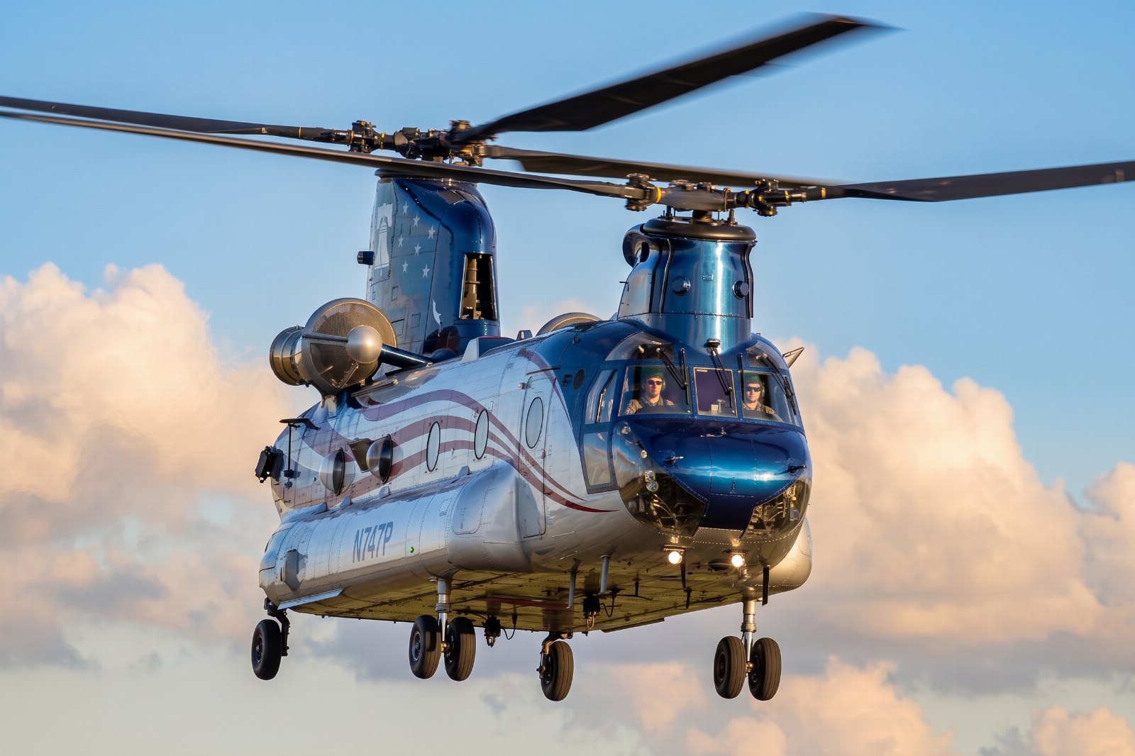 Tandem-rotor Chinook-class helicopter hovering in golden hour light